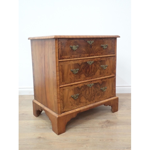 580 - A reproduction walnut Chest of small proportions with quartered moulded top fitted three drawers on ... 