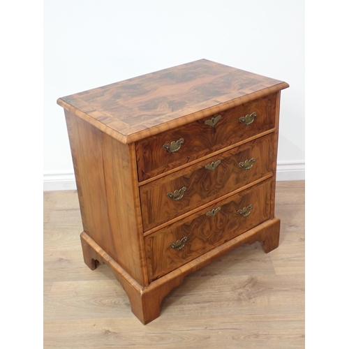 580 - A reproduction walnut Chest of small proportions with quartered moulded top fitted three drawers on ... 