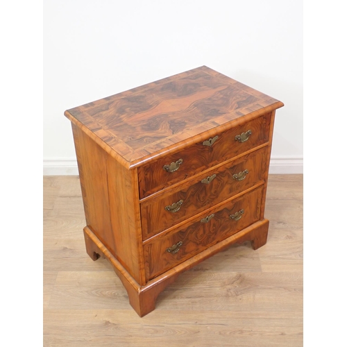 580 - A reproduction walnut Chest of small proportions with quartered moulded top fitted three drawers on ... 