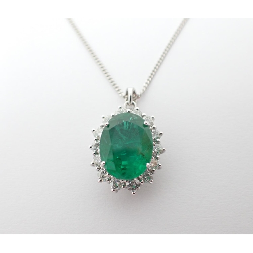 109 - An Emerald and Diamond Cluster Pendant claw-set oval-cut emerald, 3.27cts, within a frame of brillia... 