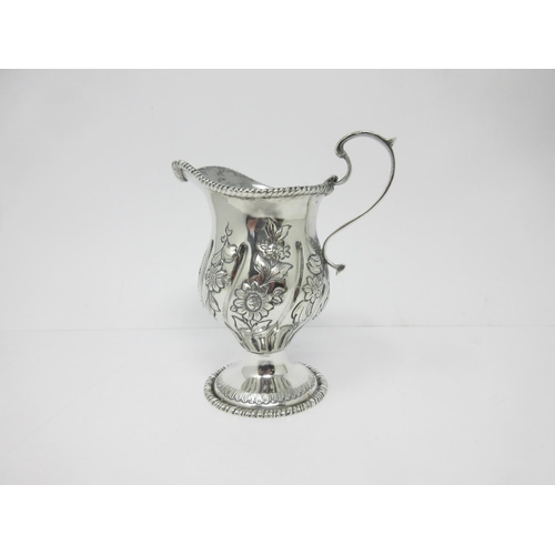 14 - An Edward VII silver helmet shape Cream Jug with floral embossing on pedestal base, Chester 1905