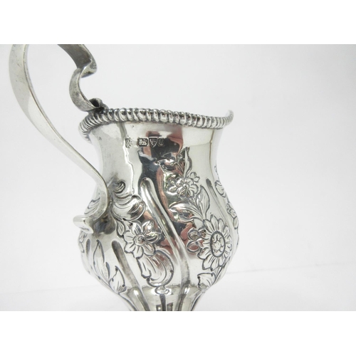 14 - An Edward VII silver helmet shape Cream Jug with floral embossing on pedestal base, Chester 1905