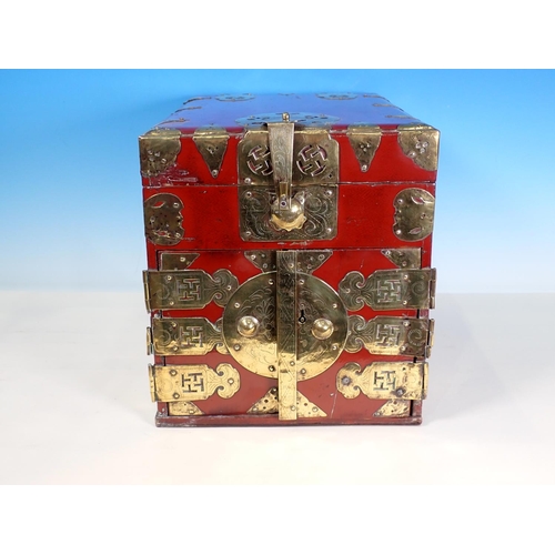 379 - A red lacquered Korean Travelling Box with decorative pierced and engraved brass fitting, having hin... 