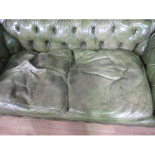 392 - A green leather button upholstered Chesterfield Settee on turned tapering supports, (reupholstered b... 