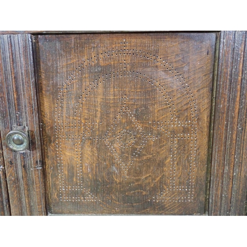 411 - A 17th Century oak Food Cupboard the pair of panelled doors with pierced arched and lozenge designs ... 