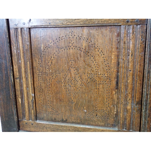 411 - A 17th Century oak Food Cupboard the pair of panelled doors with pierced arched and lozenge designs ... 