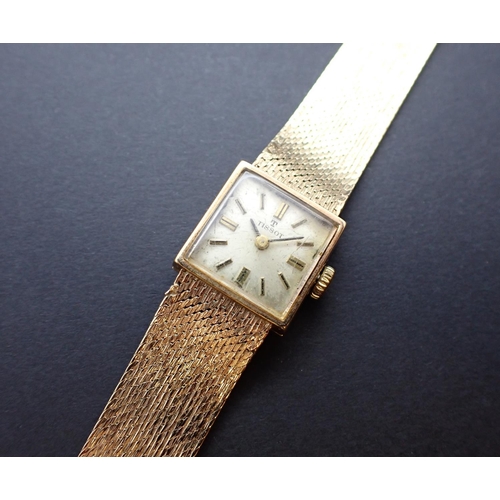 73 - A Lady's manual Tissot Wristwatch, the square champagne dial with hourly baton markers on 9ct gold f... 