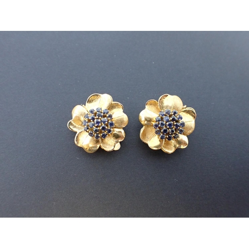 82 - A pair of Sapphire Flowerhead Ear Clips each peg-set cluster of round sapphires within frame of peta... 