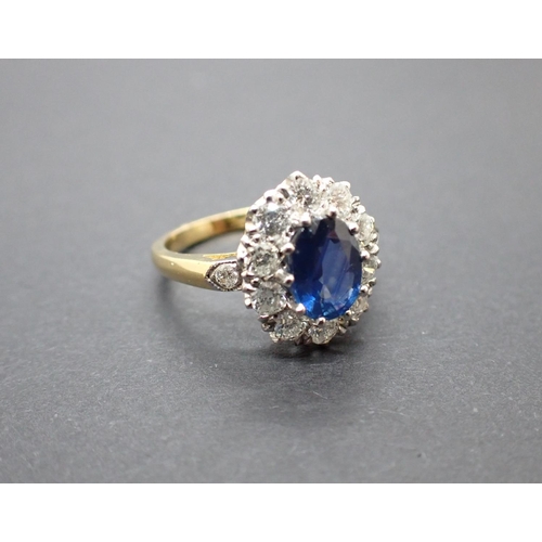 170 - A Sapphire and Diamond Cluster Ring claw-set oval-cut sapphire within a frame of ten brilliant-cut d... 