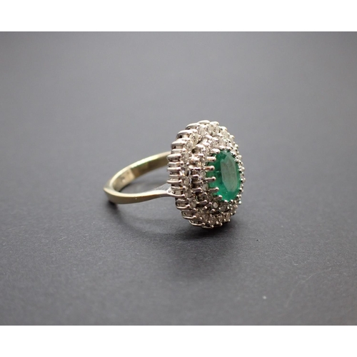 187 - An Emerald and Diamond Cluster Ring peg-set oval-cut emerald within double frame of brilliant-cut di... 