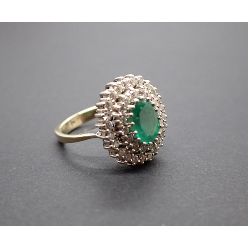 187 - An Emerald and Diamond Cluster Ring peg-set oval-cut emerald within double frame of brilliant-cut di... 