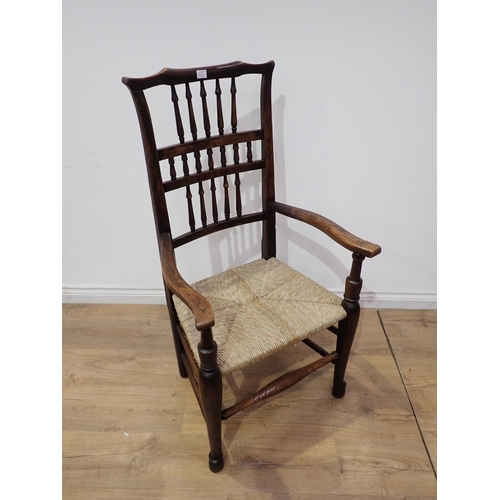 565A - A 19th Century elm rush seated spindle back Elbow Chair