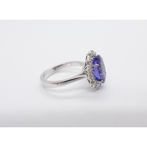 191 - A Tanzanite and Diamond Cluster Ring claw-set oval-cut tanzanite, 3.86cts, within a frame of fourtee... 