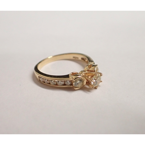 198 - A Champagne Diamond Ring claw-set brilliant-cut stone between graduated stones channel-set to should... 