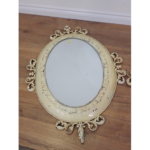 584 - A pair of cream painted oval Wall Mirrors with scroll and leafage decoration 3ft 6in W x 2ft 6in H