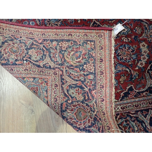 730 - A red ground Rug with floral design within dark blue border 6ft 8in L x 4ft 4in W