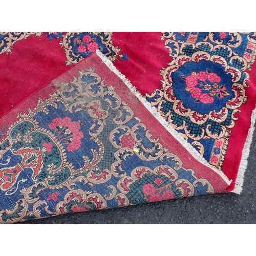 788 - A large Chinese red ground Carpet with blue central floral lozenge and broad borders 13ft L x 10ft W... 