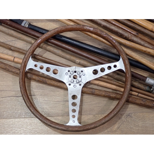 319 - A wooden racing car Steering Wheel, a quantity of Walking Sticks and two Shooting Sticks