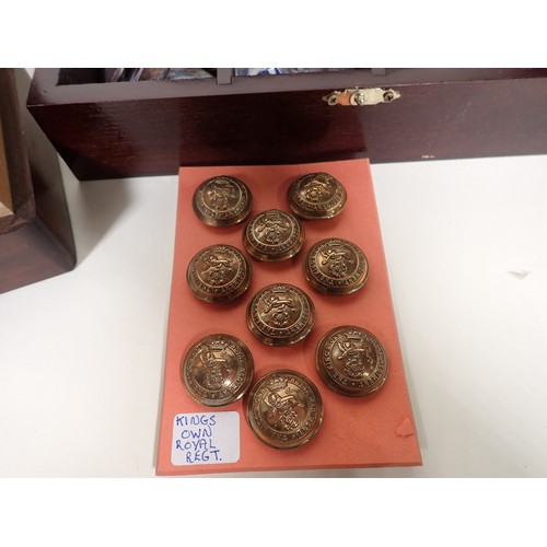 212 - Seven boxes including King's Own Royal Regiment Buttons, reproduction Military Badges, cloth Badges,... 