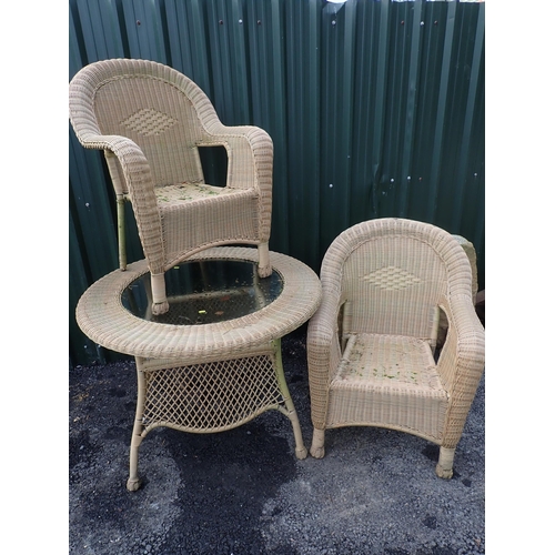 770 - A wicker effect glass topped circular Garden Table and two Chairs