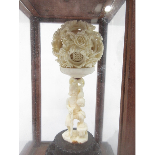 98 - An Oriental carved ivory Work Ball supported by figure, in glazed case, 14in overall