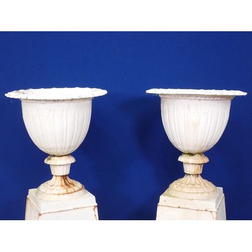 312 - A pair of antique white painted cast iron Urns on plinths with Regency Urn and Swag embossed design ... 