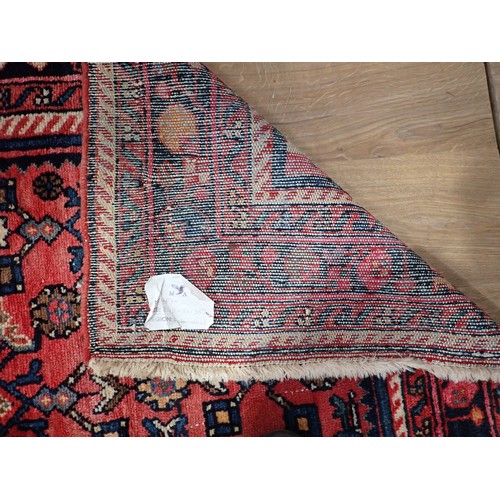 245 - A Persian Rug with multiple borders and central motif on a red ground, 8ft 2in x 4ft 10in