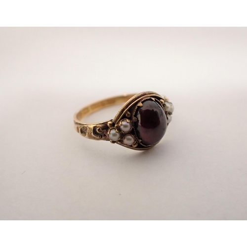 158 - A Garnet and Seed Pearl Ring claw-set oval foil backed garnet cabochon between trios of seed pearls ... 