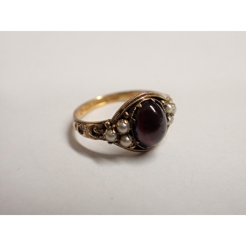 158 - A Garnet and Seed Pearl Ring claw-set oval foil backed garnet cabochon between trios of seed pearls ... 