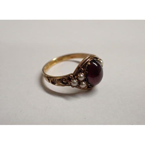 158 - A Garnet and Seed Pearl Ring claw-set oval foil backed garnet cabochon between trios of seed pearls ... 