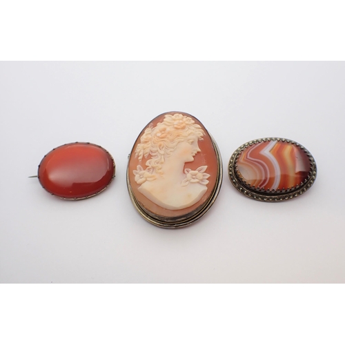 195 - A carved shell Cameo Brooch of bust in profile, an Agate Brooch and a Carnelian Brooch, all in white... 