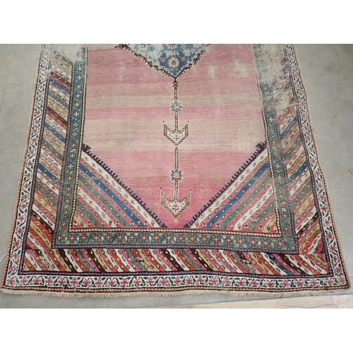 270 - A bordered Persian Rug, with central floral lozenge on a pink ground, 9ft 8in  x 5ft 1in, worn