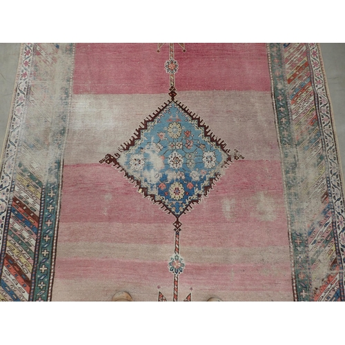 270 - A bordered Persian Rug, with central floral lozenge on a pink ground, 9ft 8in  x 5ft 1in, worn