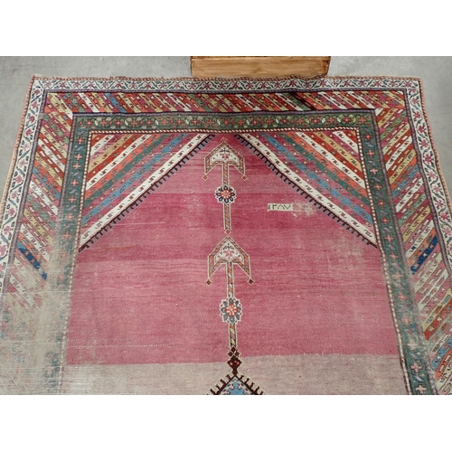 270 - A bordered Persian Rug, with central floral lozenge on a pink ground, 9ft 8in  x 5ft 1in, worn