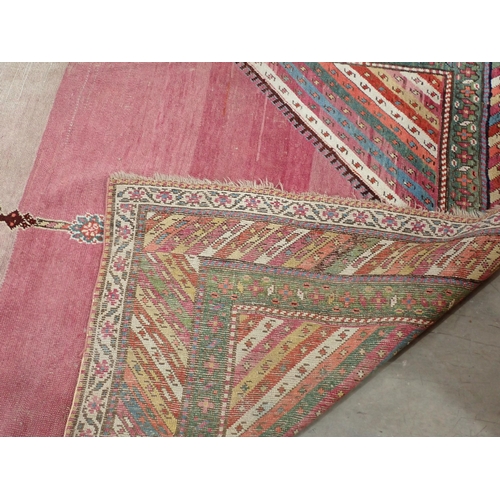 270 - A bordered Persian Rug, with central floral lozenge on a pink ground, 9ft 8in  x 5ft 1in, worn