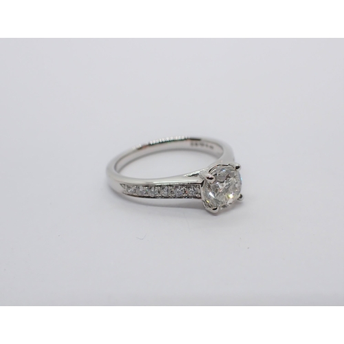 178 - A Diamond Ring claw-set brilliant-cut stone between smaller stones pavé-set to shoulders in platinum... 