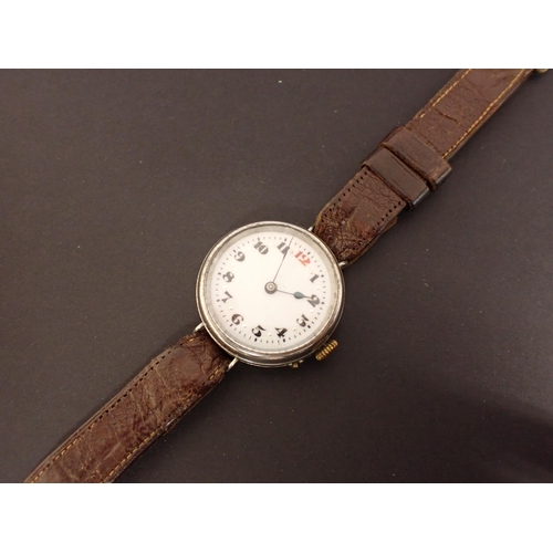 184 - A WWI Wristwatch the white enamel dial with black arabic numerals and red 12 in steel case on leathe... 