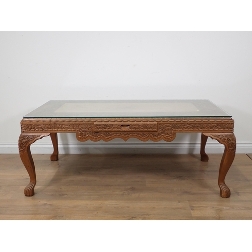 63 - An Eastern carved hardwood Coffee Table with glass top 4ft 1in W x 1ft 8in H