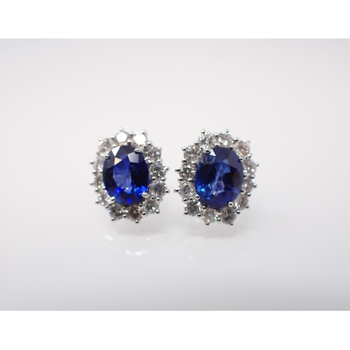 168 - A pair of Sapphire and Diamond Cluster Earrings each claw-set oval-cut sapphire, approx 2cts, within... 