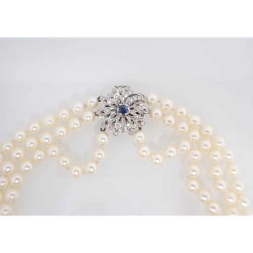 170 - A three row Cultured Pearl Choker on sapphire and diamond flower clasp in white gold. one stone defi... 