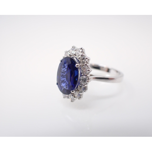 174 - A Sapphire and Diamond Cluster Ring claw-set oval-cut sapphire, 4.02cts, within a frame of fourteen ... 