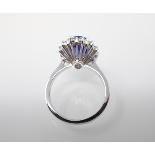 174 - A Sapphire and Diamond Cluster Ring claw-set oval-cut sapphire, 4.02cts, within a frame of fourteen ... 