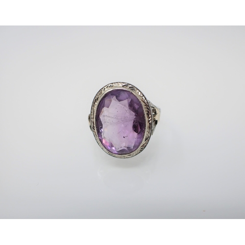 192 - An Amethyst Ring millegrain-set oval-cut stone in engraved white gold mount stamped 18K, ring size M