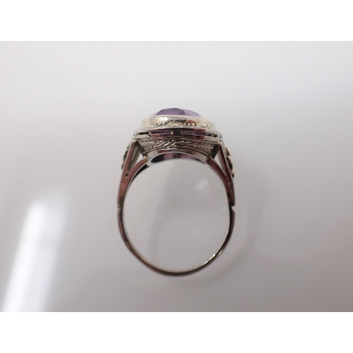 192 - An Amethyst Ring millegrain-set oval-cut stone in engraved white gold mount stamped 18K, ring size M