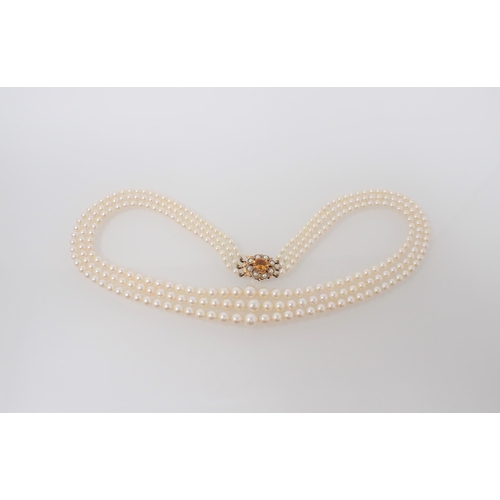 195 - A three strand graduated Cultured Pearl Necklace on 9ct gold clasp claw-set oval-cut citrine within ... 