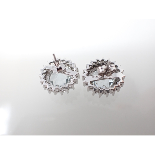 198 - A pair of Blue Topaz and Diamond Cluster Earrings claw-set round multi-faceted topaz within a frame ... 