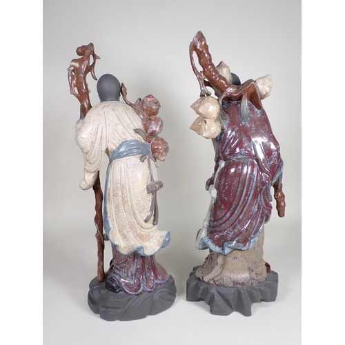 379 - A large pair of Lladro Chinese Figures holding staffs and carrying fruit, in coloured glazes and ung... 