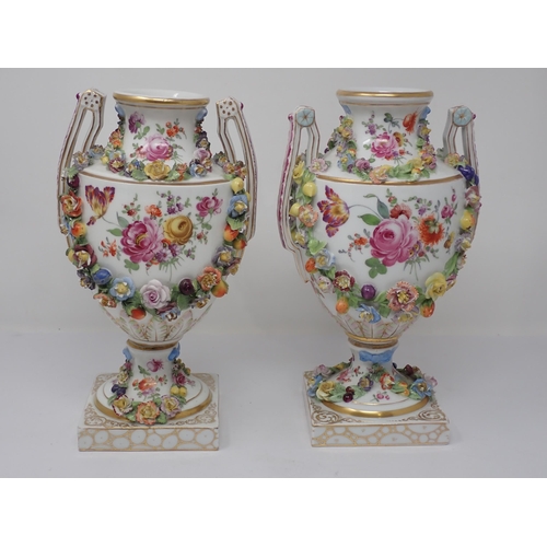 395 - A pair of Dresden pedestal two handled Vases, painted classical figures and floral sprays opposing w... 