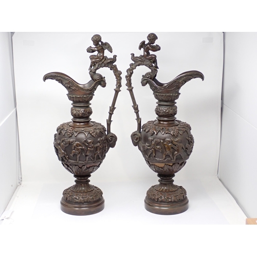 459 - A pair of 19th Century bronze Ewers with handles terminated with Putti and the bodies each with a fr... 