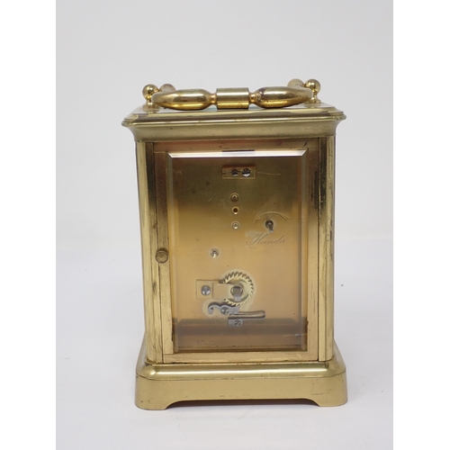 513 - A brass cased Carriage Clock, the enamel dish marked with Roman numerals, name indistinct, 5¼in H